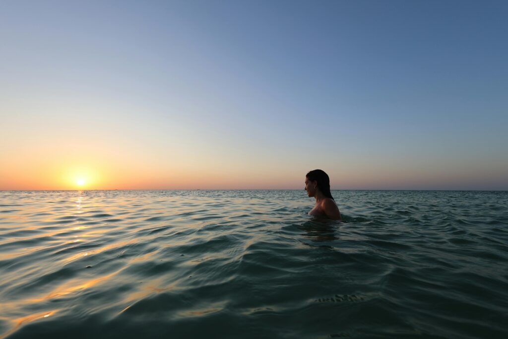A person swimming in the Caribbean Sea enjoying a tranquil sunset view. Ideal for travel and relaxation themes.