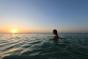 A person swimming in the Caribbean Sea enjoying a tranquil sunset view. Ideal for travel and relaxation themes.